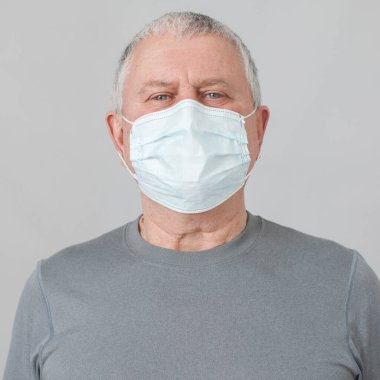 Sağlık maskeli son sınıf öğrencisi gri arka planda izole edildi