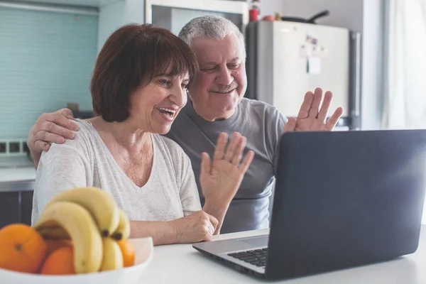 Pareja mayor mirando el ordenador en la cocina — Foto de Stock