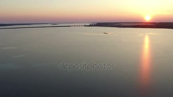 Let nad velkým zamrzlé jezero s mostem v zimě na západ slunce, letecký pohled. — Stock video