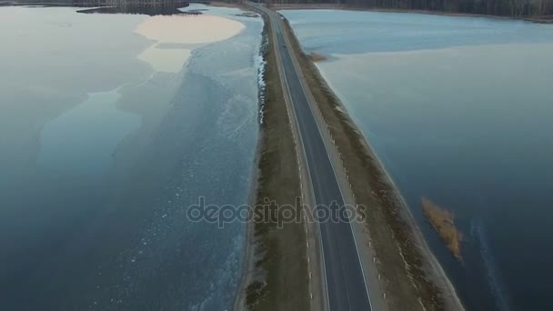 Vuelo sobre la carretera en el lago congelado en invierno al atardecer, vista aérea . — Vídeos de Stock