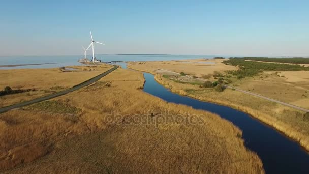 4K. Політ над блакитною річкою і полями в бік вітрових турбін біля моря, вид з повітря на захід сонця — стокове відео