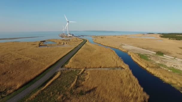 4K. Vista aérea con turbinas eólicas giratorias, río azul, campos y carretera cerca del mar — Vídeo de stock