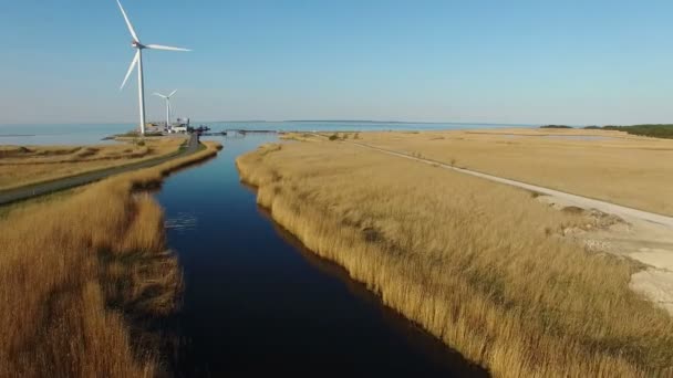 4K. Vol au-dessus d'une rivière bleue et champs vers des éoliennes près de la mer, vue aérienne au coucher du soleil — Video