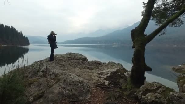 4K. A menina faz foto do incrível lago Bohinj, vista panorâmica. Julian Alps, Parque Nacional de Triglav, Eslovénia, Europa. Hora de Inverno — Vídeo de Stock