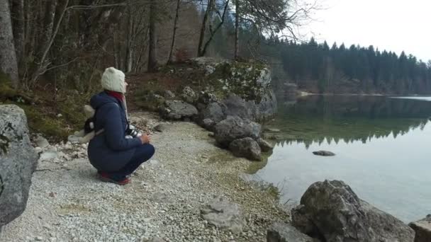 4K. La niña está descansando y mirando al lago Bohinj, vista panorámica.Alpes, Parque Nacional Triglav, Eslovenia, Europa. Tiempo de invierno — Vídeos de Stock