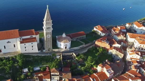 Vuelo sobre la ciudad vieja Piran en Eslovenia, vista aérea de pájaro con casas antiguas, Iglesia Parroquial de San Jorge y el mar — Vídeo de stock