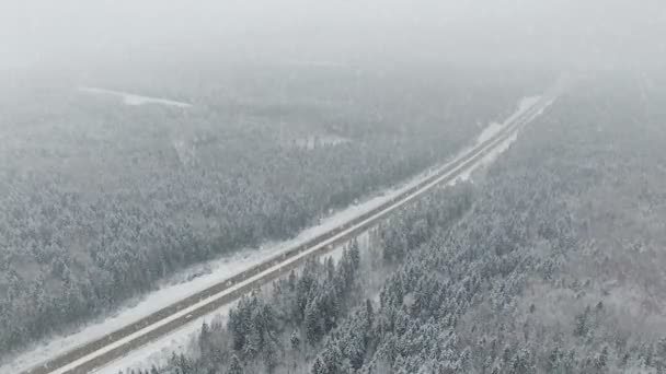 4 k. Road i skogen vintern med att köra bilar på snöfall. Panoramautsikt över Flygfoto. Gränspunkt perspektiv. — Stockvideo