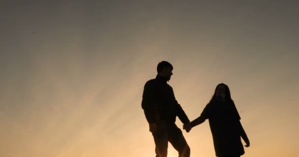 Silhouette of happy couple enjoying sunset together, looking in future with hope