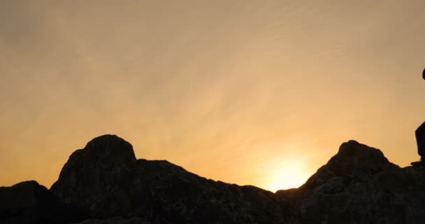 Zwei gehen auf Felsen, gegen einen Sonnenuntergang. — Stockvideo