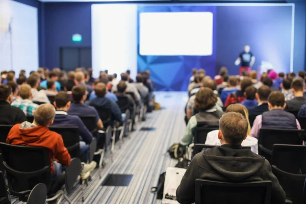 Business and entrepreneurship symposium. Speaker giving a talk at business meeting. Audience in the conference hall. Rear view of unrecognized participant in audience. — Stock Photo, Image