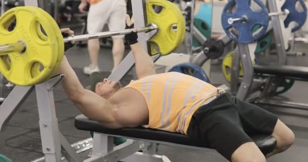 Hombre deportivo guapo está haciendo ejercicio en el centro de gimnasia — Vídeos de Stock