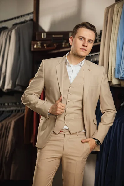 Elegante joven apuesto hombre. Un hombre joven y elegante con una chaqueta de tela azul. Está en la sala de exposición, probándose ropa, posando. Publicidad foto — Foto de Stock
