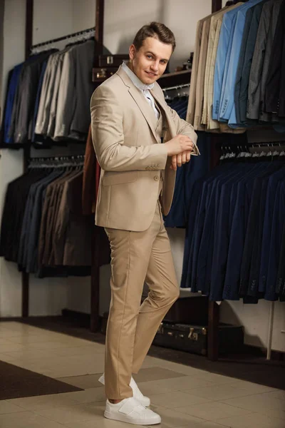 Elegante joven apuesto hombre. Un hombre joven y elegante con una chaqueta de tela azul. Está en la sala de exposición, probándose ropa, posando. Publicidad foto — Foto de Stock