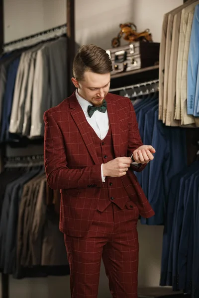 Handsome young bearded businessman in classic suit. A young stylish man in a jacket. It is in the showroom, trying on clothes, posing. Advertising photo