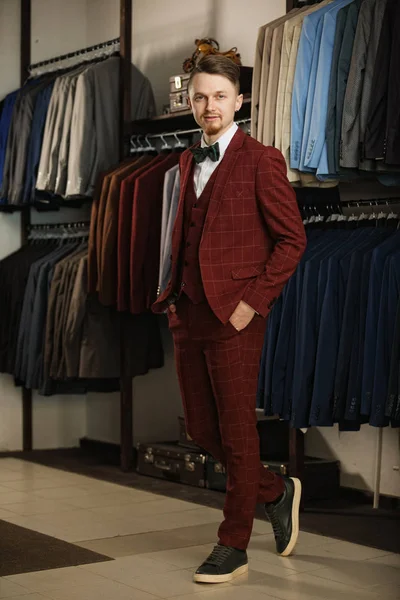 Joven hombre de negocios barbudo guapo en traje clásico. Un hombre joven y elegante con chaqueta. Está en la sala de exposición, probándose ropa, posando. Publicidad foto — Foto de Stock