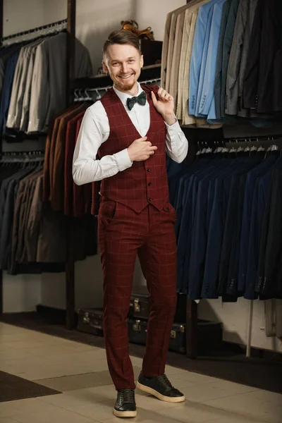 Handsome young bearded businessman in classic suit. A young stylish man in a jacket. It is in the showroom, trying on clothes, posing. Advertising photo