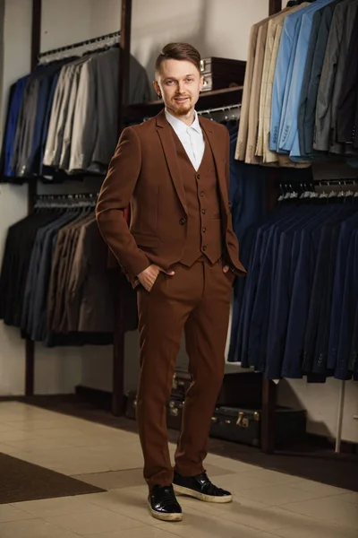 Handsome young man in classic suit. It is in the showroom, trying on clothes, posing. Advertising photo