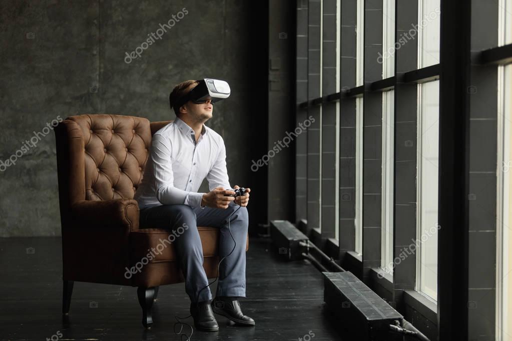 Man wearing virtual reality goggles. Interior shot, gray background