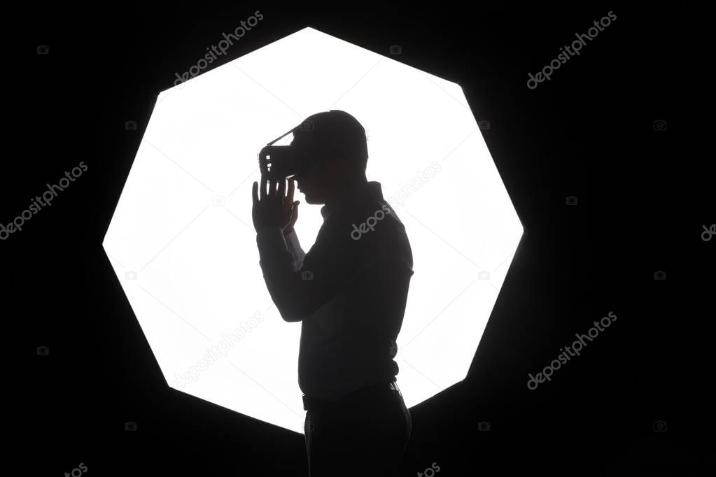 Man wearing virtual reality goggles watching movies or playing video games. Standing near the window, side view, white background
