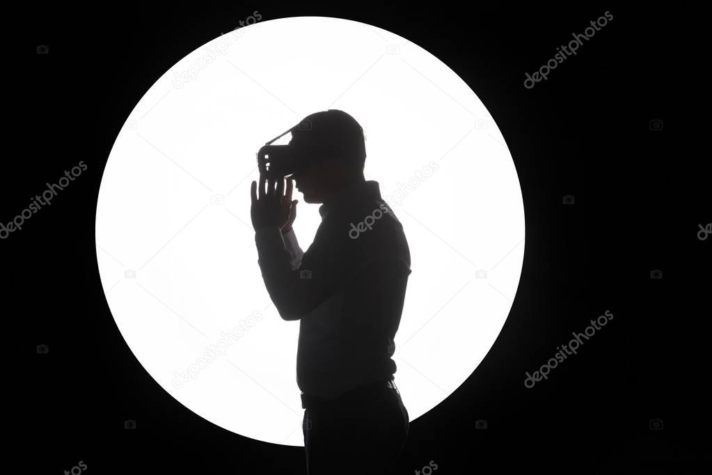 Man wearing virtual reality goggles watching movies or playing video games. Standing near the window, side view, white background