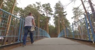 bir parkta yürüyüş onun longboard olan adam. İzleme atış