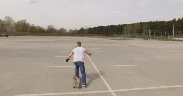 Mann auf Longboard-Skate auf einem Parkplatz. Kamerafahrt — Stockvideo