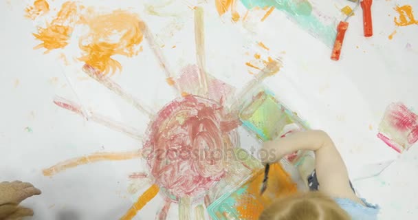 Симпатичный ребенок, играющий с красками и создающий беспорядок. — стоковое видео