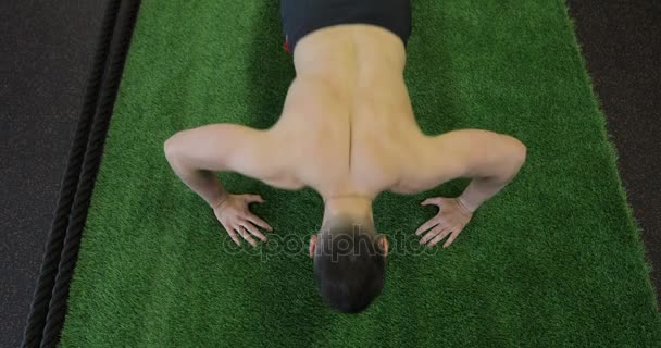 Deportista haciendo ejercicio en el gimnasio. Musculoso joven haciendo flexiones en la esterilla de ejercicio . — Vídeos de Stock