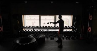 Atletik erkek adam dumbbells ile Halter spor salonu siyah arka plan ile çalışma dışarı silüeti. Fitness.