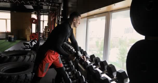 Сильний чоловік робить вправи з гантелями — стокове відео