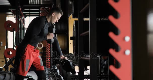 Красивый спортсмен тренируется с гантелями в спортзале — стоковое видео