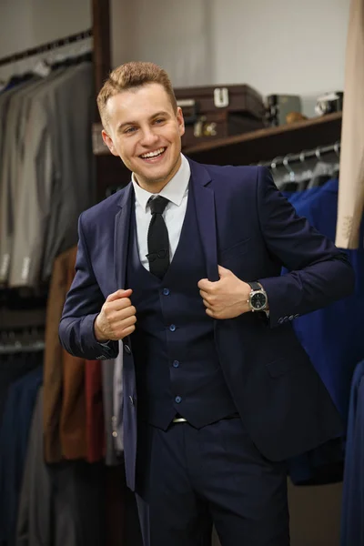 Elegante jonge knappe man. Een stijlvolle jongeman in een zwarte doek jasje. Het is in de showroom, proberen op kleding, poseren. Reclame foto — Stockfoto