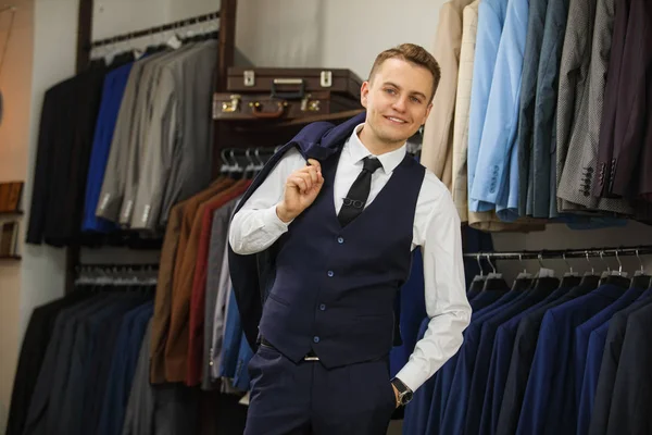 Elegante jonge knappe man. Een stijlvolle jongeman in een zwarte doek jasje. Het is in de showroom, proberen op kleding, poseren. Reclame foto — Stockfoto