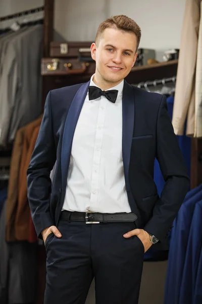 Elegante joven apuesto hombre. Un hombre joven y elegante con una chaqueta de tela negra. Está en la sala de exposición, probándose ropa, posando. Publicidad foto — Foto de Stock