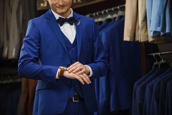 Un hombre joven y elegante con una barba en una chaqueta de tela vintage. Está en la sala de exposición, probándose ropa, posando. Publicidad foto — Foto de Stock