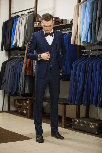 Een jonge stijlvolle man met een baard in een vintage doek jasje. Het is in de showroom, proberen op kleding, poseren. Reclame foto — Stockfoto