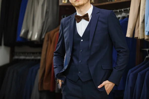 Un hombre joven y elegante con una barba en una chaqueta de tela vintage. Está en la sala de exposición, probándose ropa, posando. Publicidad foto — Foto de Stock