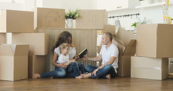 Rodinné stěhování. Rodiče a děti vybalování krabic. Přesun rodiny relaxační a směje se po rozbalení krabičky od domu