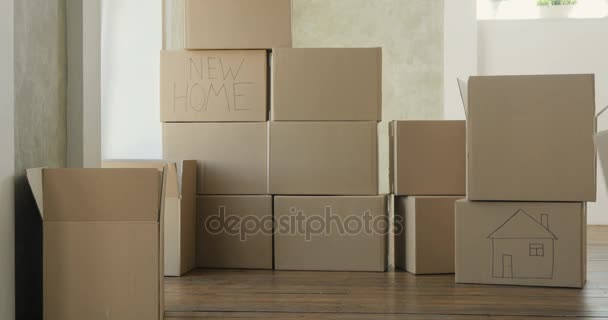 Criança ajuda os pais com se muda para um novo apartamento, bebê carrega caixas. Mudar para um novo conceito de apartamento — Vídeo de Stock