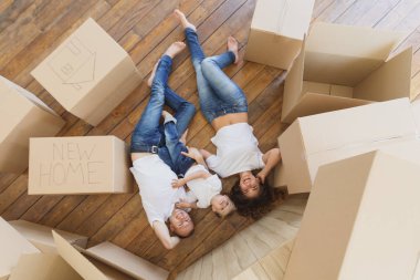 Üstten Görünüm yakışıklı baba ve annenin oynamak ve küçük oğulları yerde yatarken sarıl. Aile rahatlatıcı ve karton ev taşıma,--dan açmak sonra gülerek görüntülemek en baştan