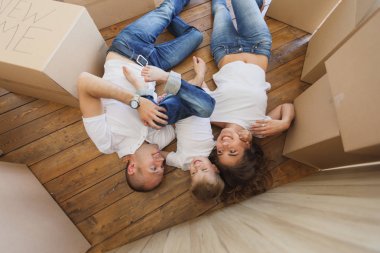 Üstten Görünüm yakışıklı baba ve annenin oynamak ve küçük oğulları yerde yatarken sarıl. Aile rahatlatıcı ve karton ev taşıma,--dan açmak sonra gülerek görüntülemek en baştan