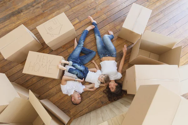 La famiglia gioca nel loro nuovo appartamento. Vista dall'alto sulla giovane famiglia che si muove in una nuova casa e disfa le scatole — Foto Stock