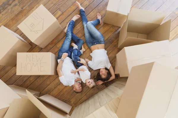 La famiglia gioca nel loro nuovo appartamento. Vista dall'alto sulla giovane famiglia che si muove in una nuova casa e disfa le scatole — Foto Stock