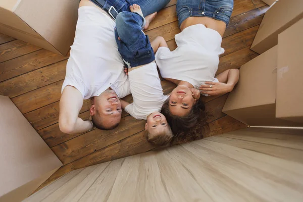 Семья играет в своей новой квартире. Вид сверху на молодую семью, переезжающую в новый дом и распаковывающую коробки — стоковое фото