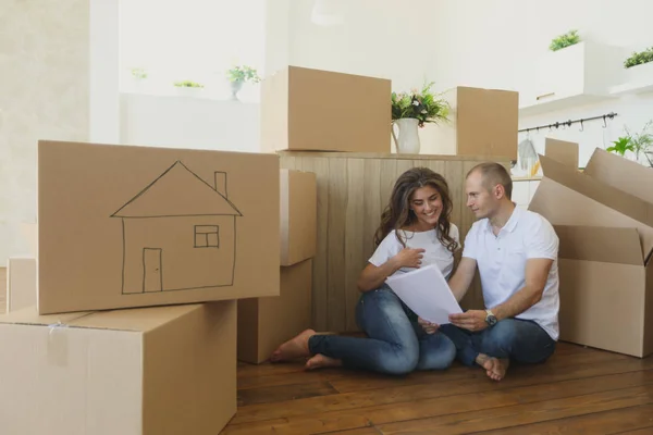 Пара планирующих свою новую кухню, сидящую на полу. молодая семья переезжает в новую квартиру и несет коробки — стоковое фото