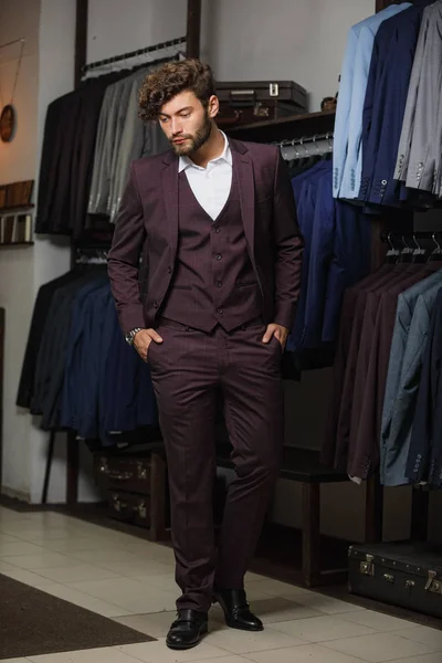 Homem de negócios bonito jovem moderno vestido em terno clássico ajustando um empate enquanto estava na loja de terno — Fotografia de Stock
