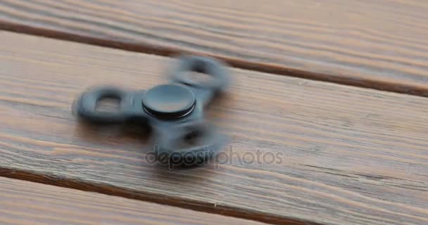 A high speed spinning hand spinner or fidget spinner over the wooden background. — Stock Video