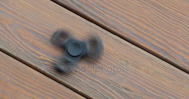 Hand spinner of fidgeting spinner, draaien op de verdieping. houten achtergrond. — Stockvideo