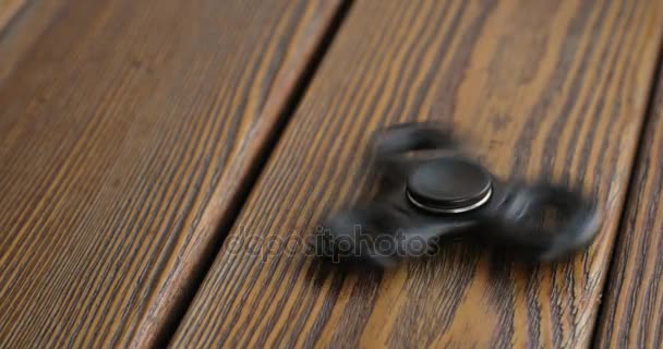 Hand spinner of fidgeting spinner, draaien op de verdieping. houten achtergrond. — Stockvideo