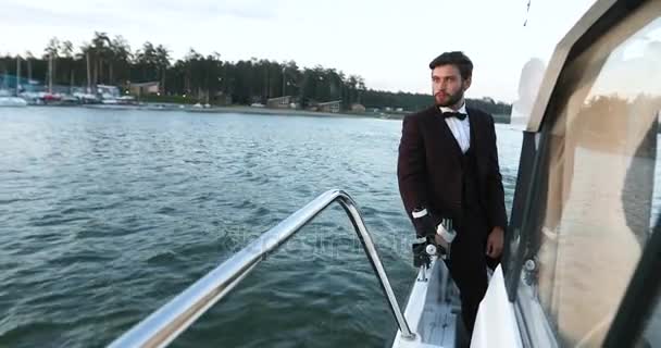 Stylish businessman on a yacht or boat against a sea. He is pleased with the success in his business and his team Partner, were in Business Luxury traveling and working. — Stock Video